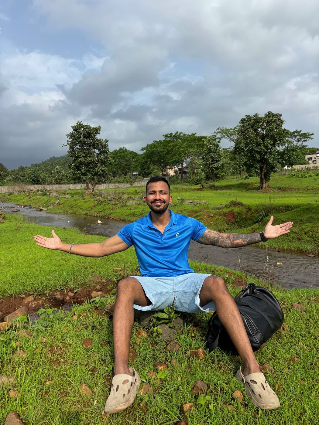 Ninad with arms wide open in a green valley