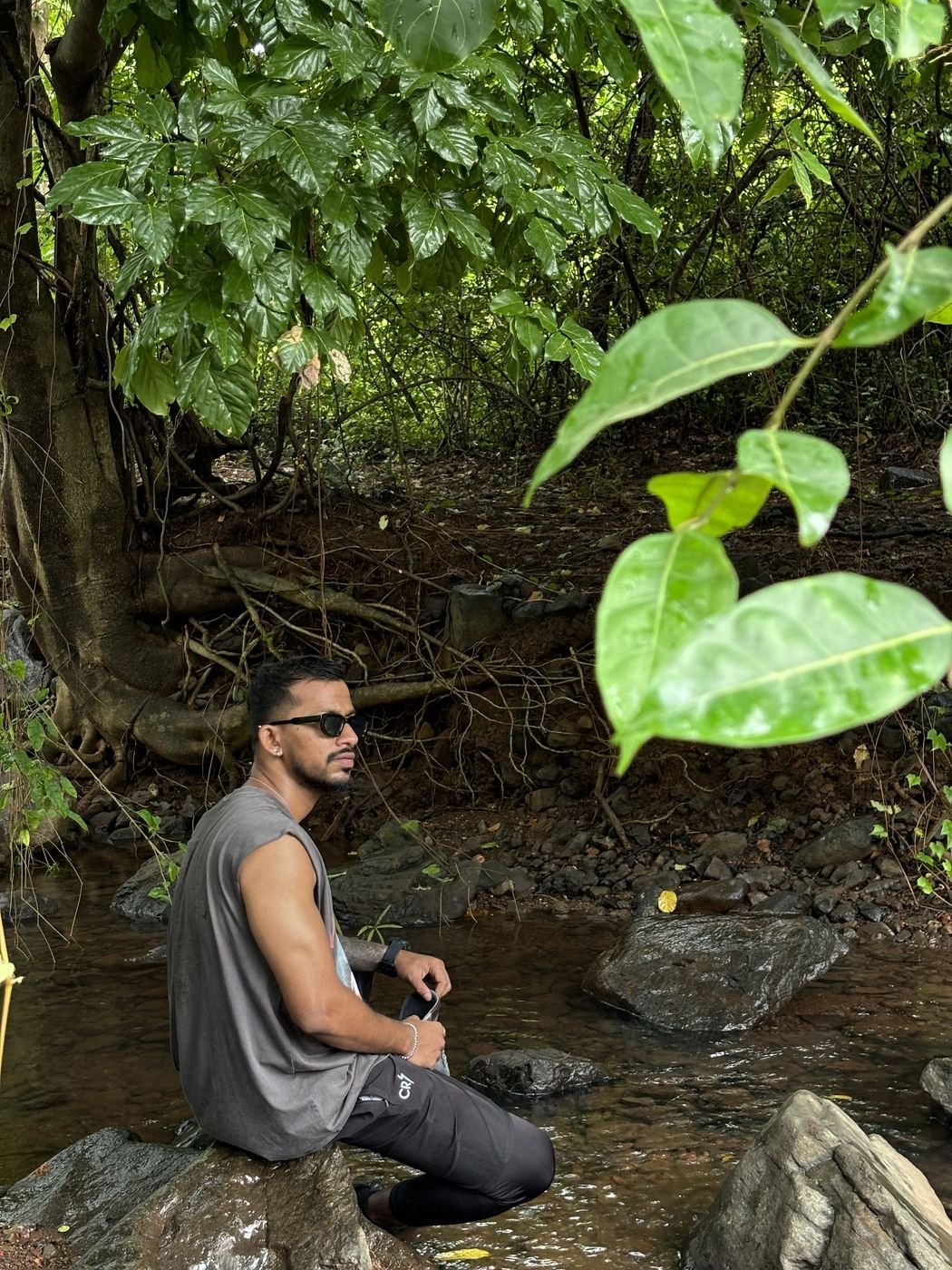 Ninad by a forest stream in sunglasses