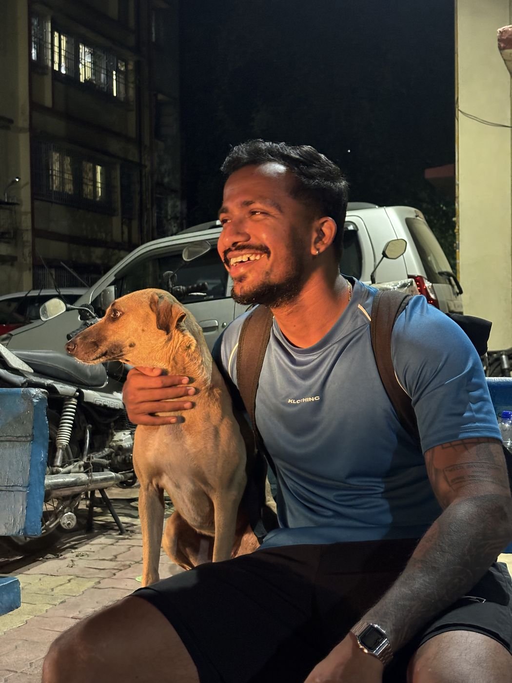 Ninad laughing with a street dog at night