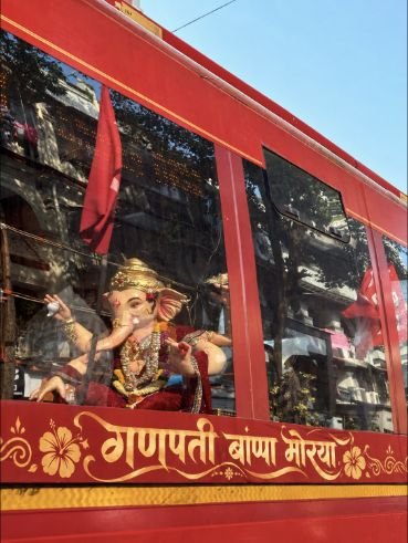 Ganpati idol in a red bus marked Ganpati Bappa Morya